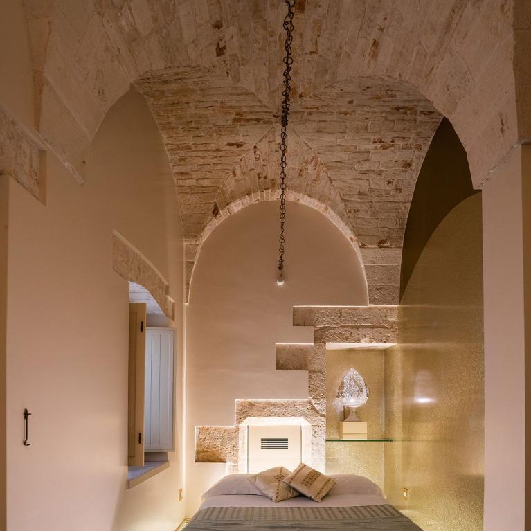 Bedroom with suspended bed and glass floor with white pebbles.