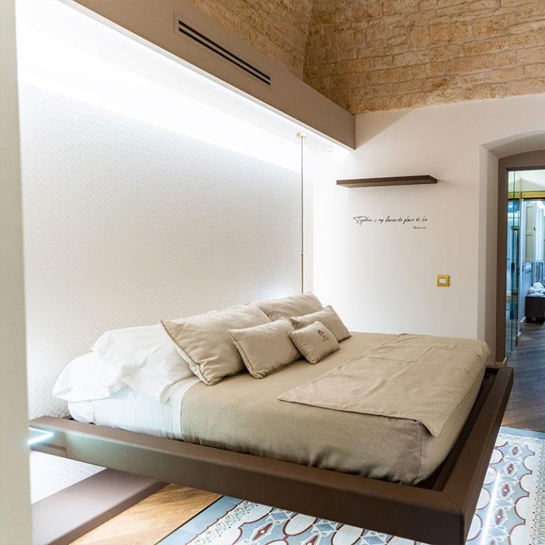 Camera da letto moderna con letto sospeso e pareti in pietra.