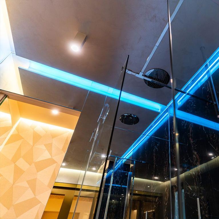 Moderno bagno con doccia in vetro e illuminazione LED blu.