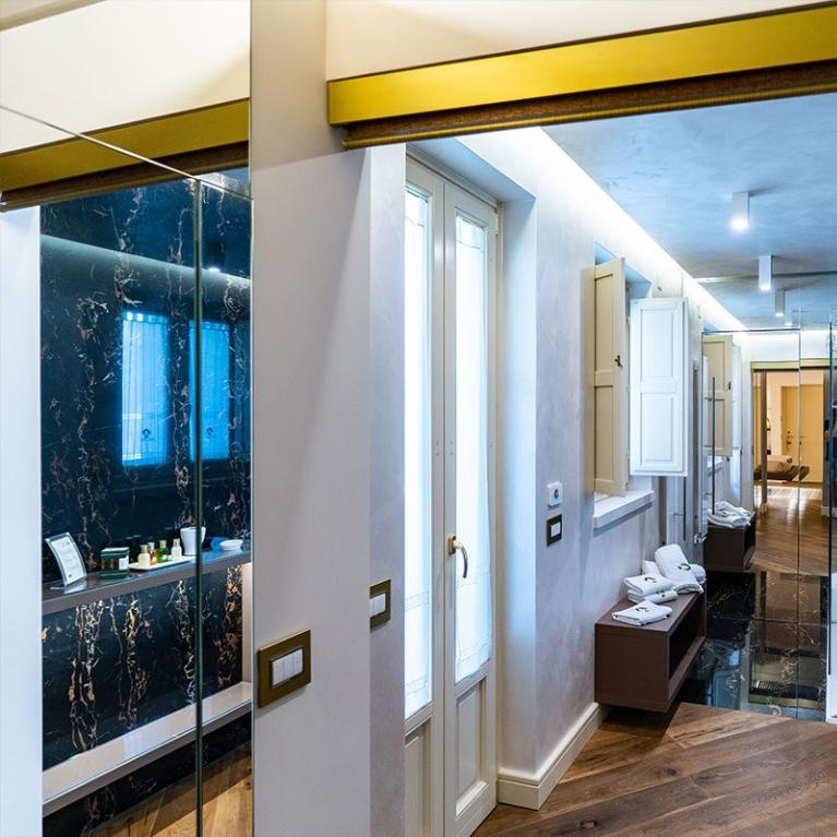 Bagno moderno con pavimento in legno e pareti in marmo nero.