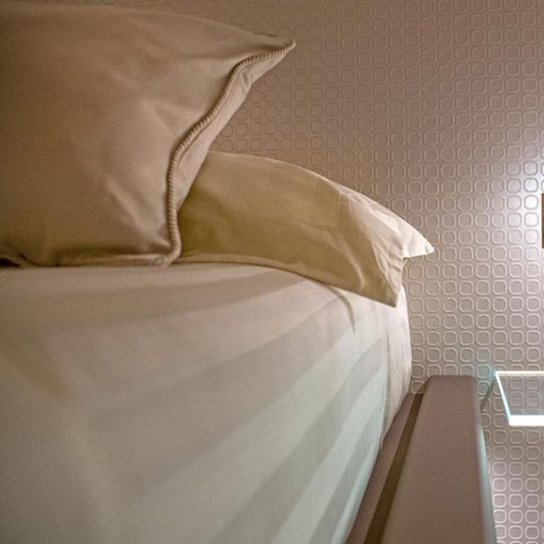 Camera da letto moderna con illuminazione a parete e mensola di vetro.