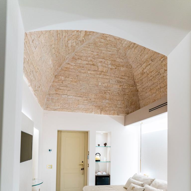 Camera moderna con soffitto in pietra, letto sospeso e pavimento in legno.