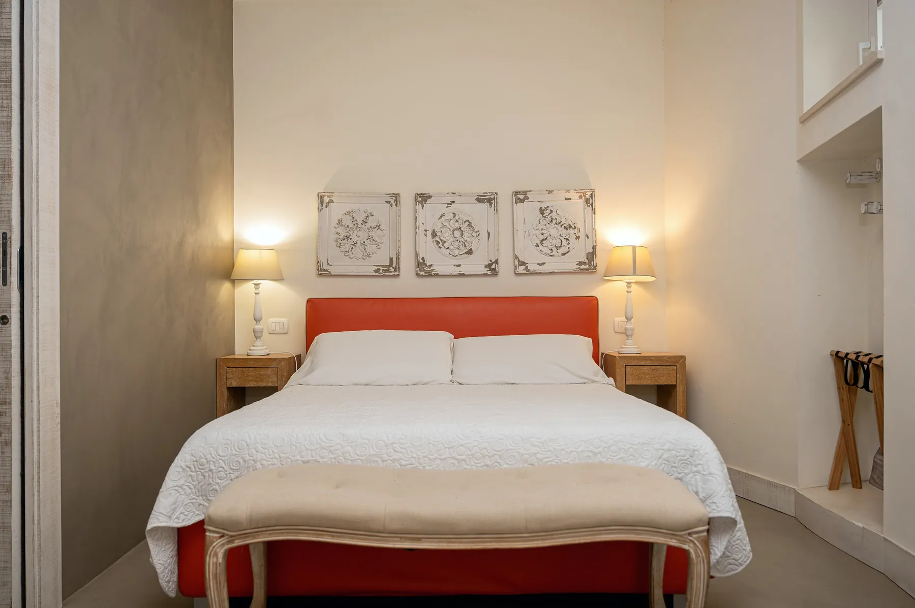 La Piccola Double Economy: a double bed with an orange headboard, three tiles on the wall above and two lamps.