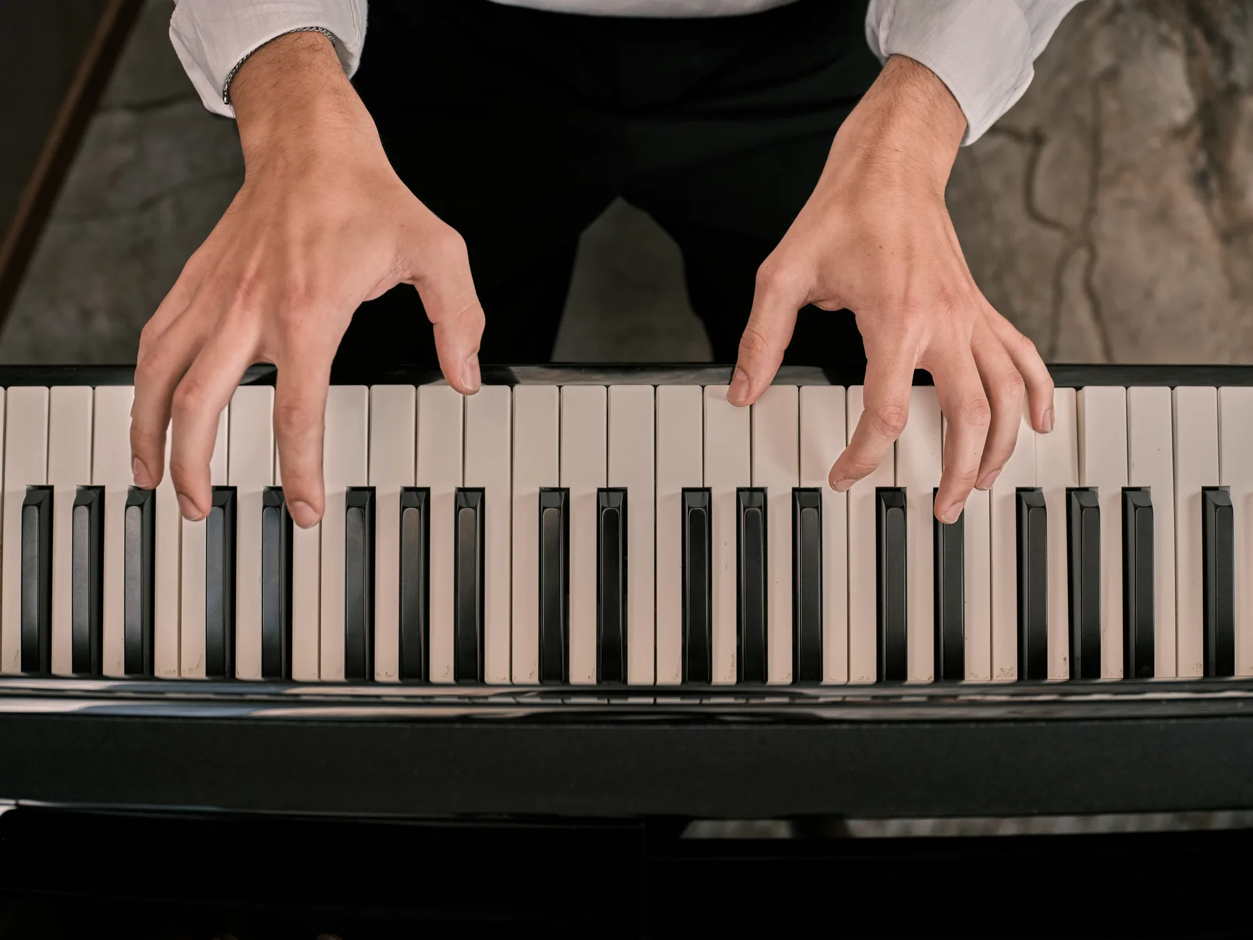 Two hands on the keys of a piano seen from above, in the NOS dining room.